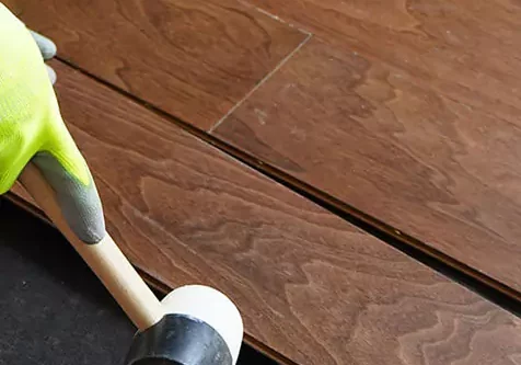 Mallet tapping in hardwood plank | Coleman's Flooring & Blinds